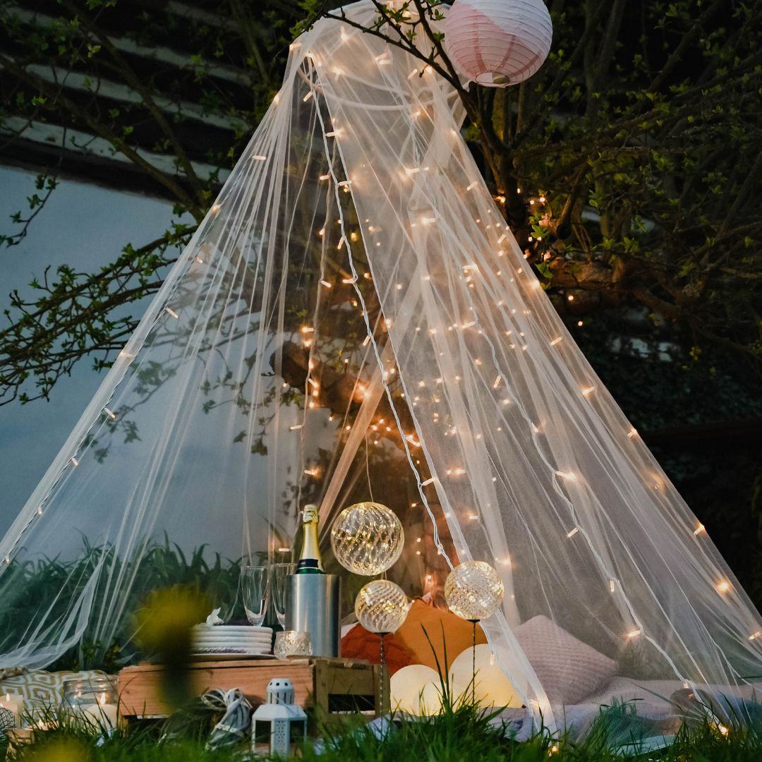 Gartenpavillon aus Tüll mit LED-Lichterkette, Picknickutensilien und Laternen